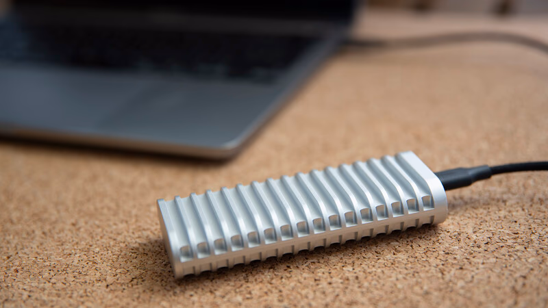 Aluminum ribbed heat sink with attached black cable on cork desktop surface